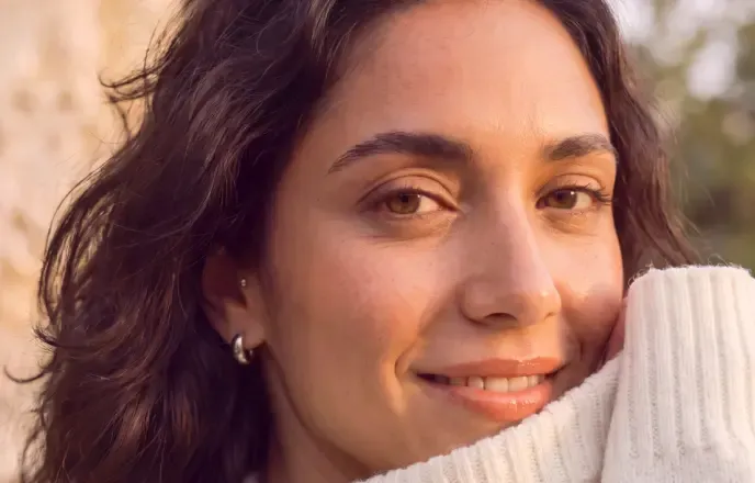 A smiling woman in a cream sweater