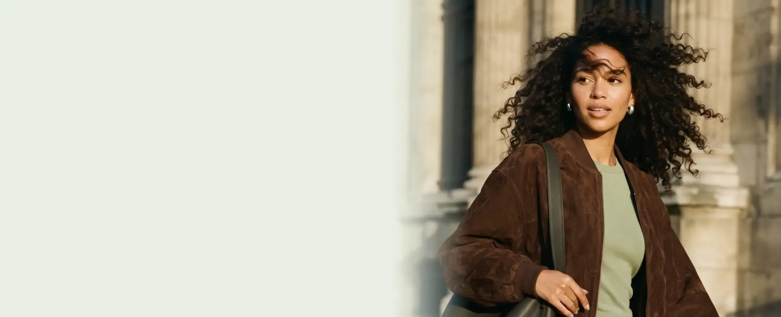 A woman walking through the city with a shoulder bag